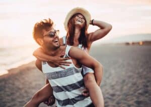 Young couple beach piggyback happy, couples therapy Los Angeles, CA, relationship goals, communication skills, joy together