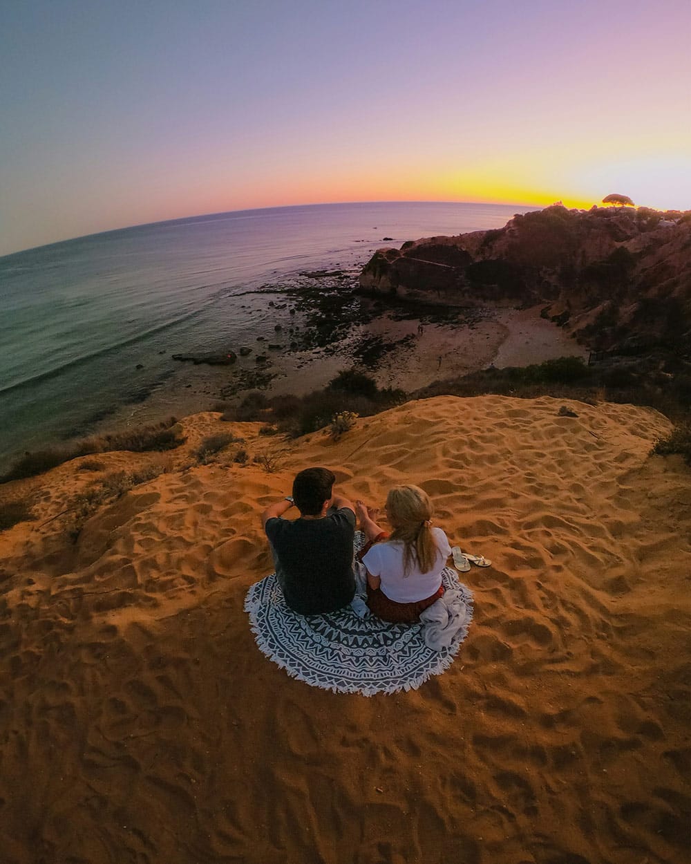 A man lifts a laughing woman in a denim jacket