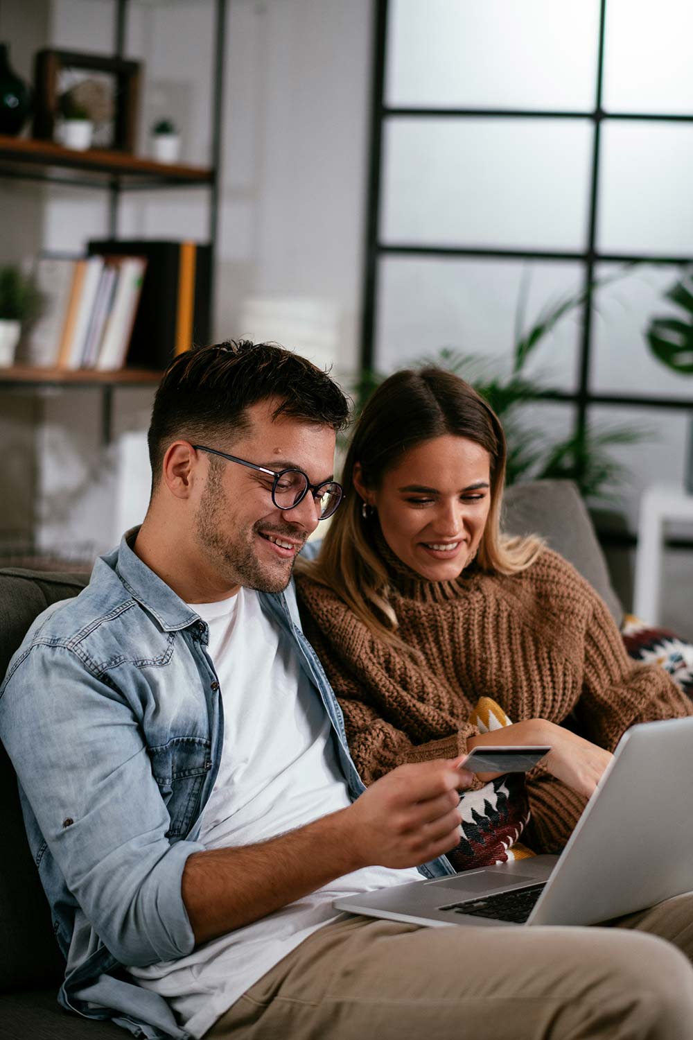 A couple smiles while sitting on a couch