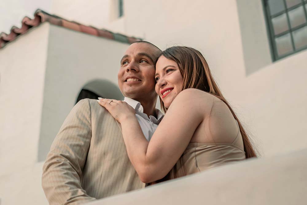 A man and a woman embracing each other in front of a building.