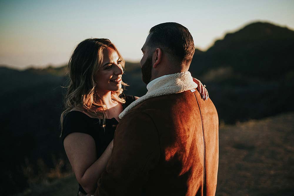 A man standing next to a woman on top of a hill.