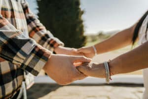 Close-up of a couple holding hands outdoors.