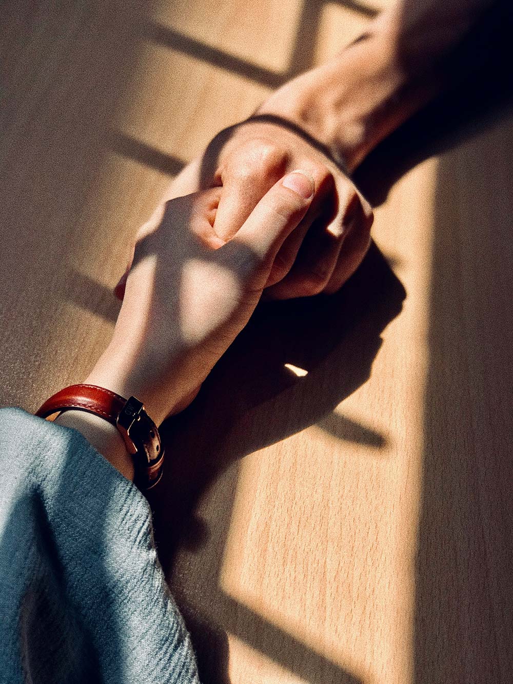 Hands clasp together on a wooden table