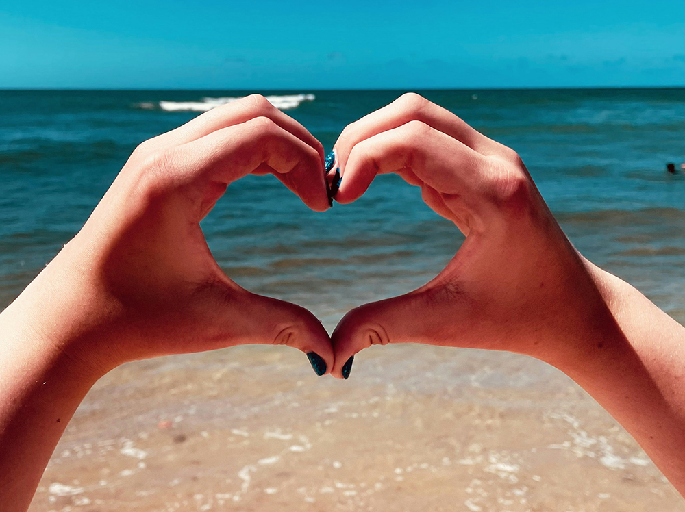Two Hands Making a Heart Shape on a Beach