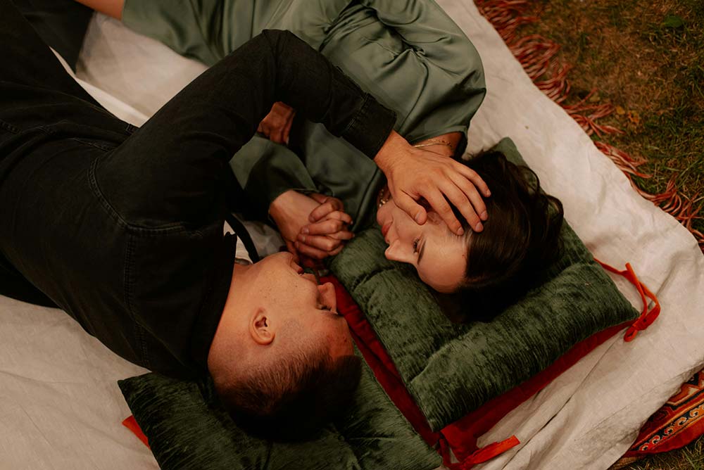 Two people lying on a blanket on the ground.