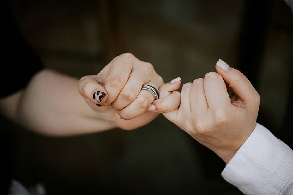 Two people making a "pinky swear" gesture.