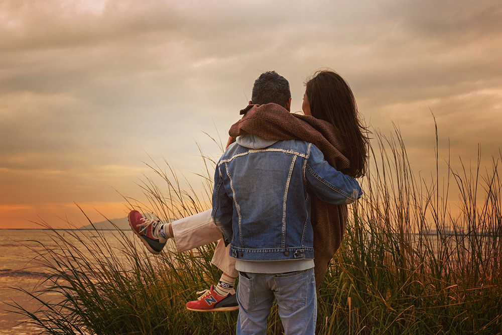 Woman in a Blue Denim Jacket and Blue Denim Jeans Standing on Green Grass