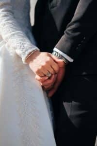 close-up of a bride and groom holding hands.