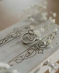 close-up of wedding rings on a wooden box with baby's breath flowers.