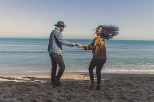couple dancing on sandy beach by the ocean