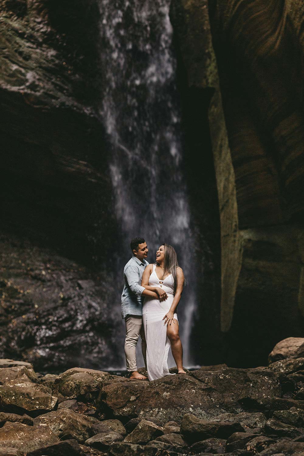 couple embracing in front of tall waterfall