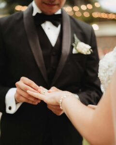 groom placing a wedding ring on the bride's finger.