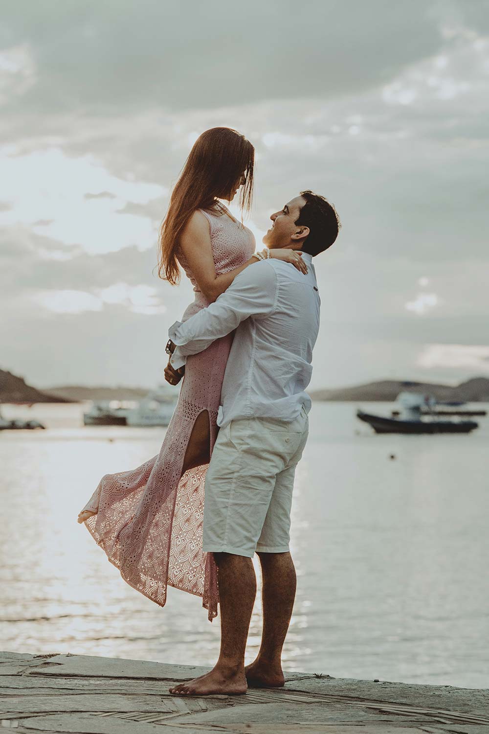 couple in wedding attire embracing on a cliff by the ocean.