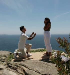 man proposing to a woman on a cliff overlooking the ocean.