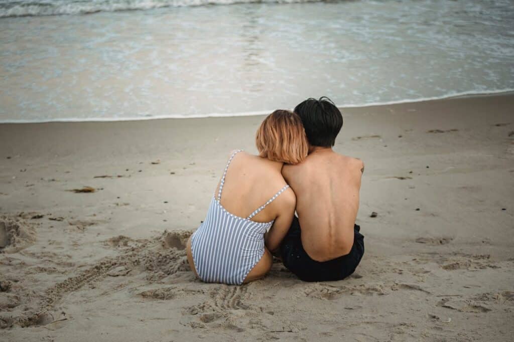 Couple sitting closely on a Florida beach looking at the ocean, symbolizing emotional connection.