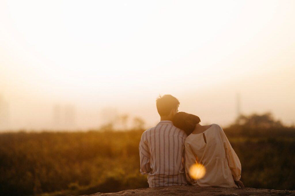 A couple sitting close together at sunset, symbolizing emotional distance and reconnection in marriage.