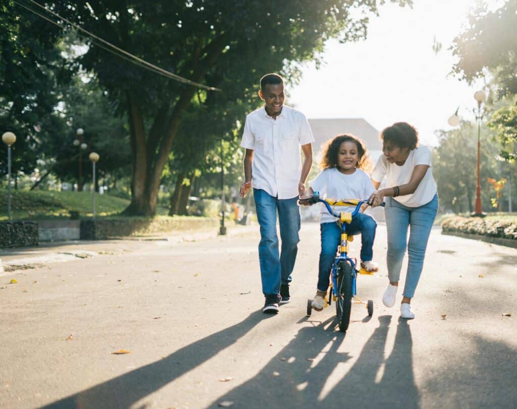 Parents in Florida helping their child ride a bike, symbolizing teamwork and family bonding.