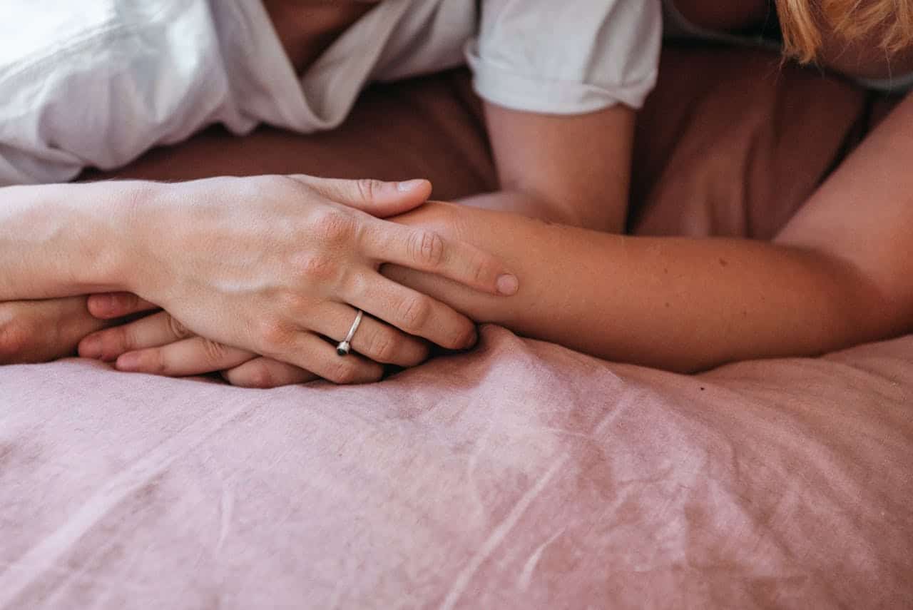 Couple holding hands on a bed reflecting on emotional connection before marriage
