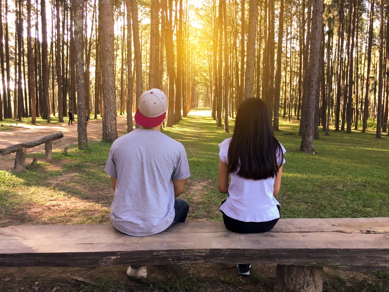 Couple sitting side by side on a wooden bench in a peaceful forest, reflecting and having a deep conversation.
