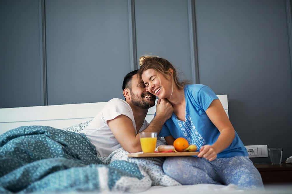 couple standing under tree with reddish leaves