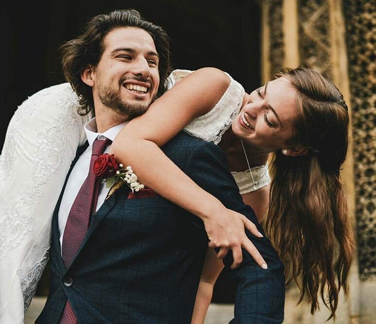 smiling groom carrying his bride over his shoulder.